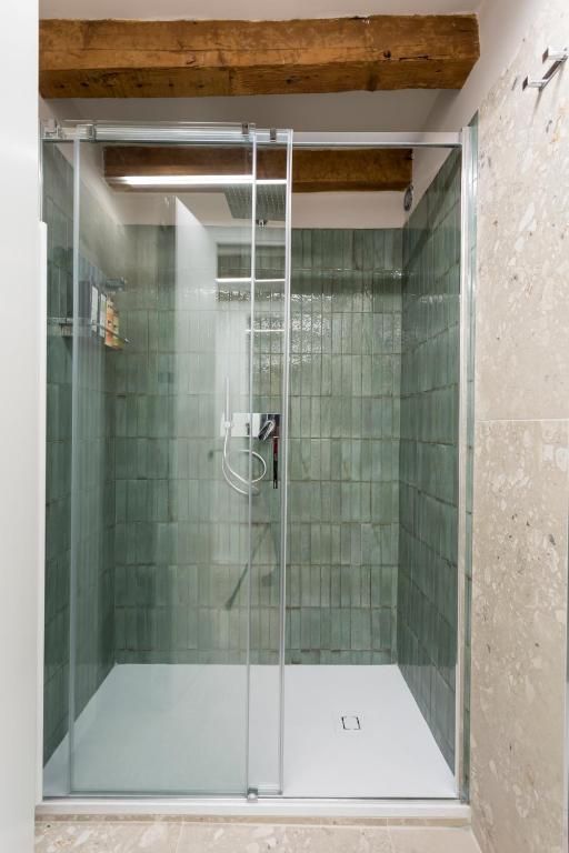 Un bagno con porta doccia scorrevole in vetro e piastrelle verdi.