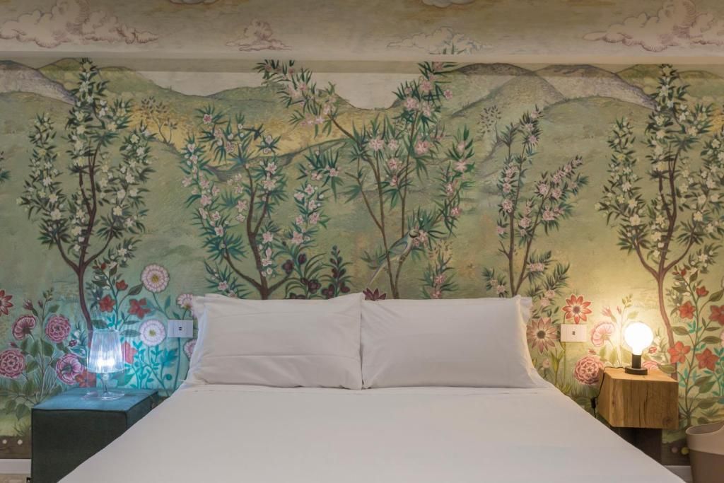 Un letto in una camera da letto con una carta da parati floreale alla parete.