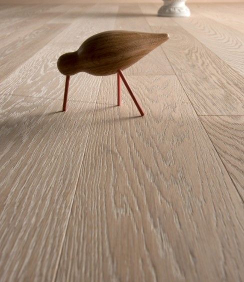 Un piccolo uccellino di legno è in piedi su un pavimento di legno