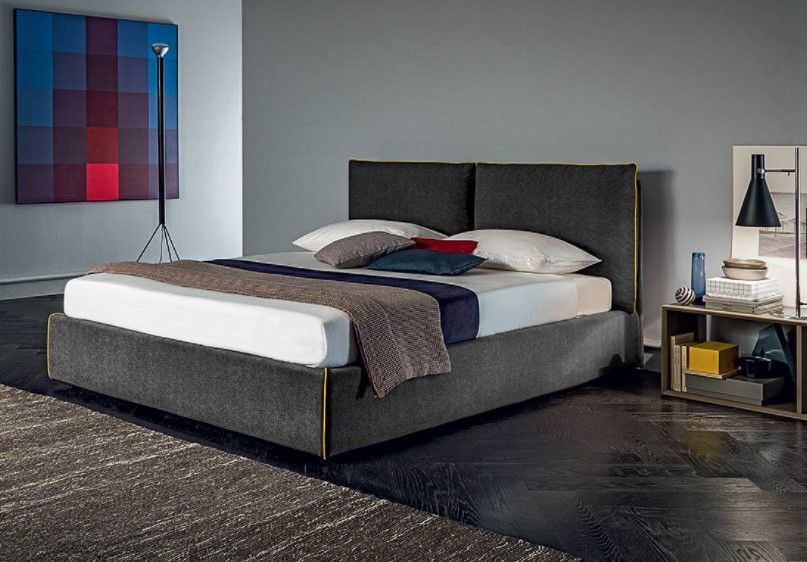 Una camera da letto con un letto, un comodino, una lampada e un quadro alla parete.
