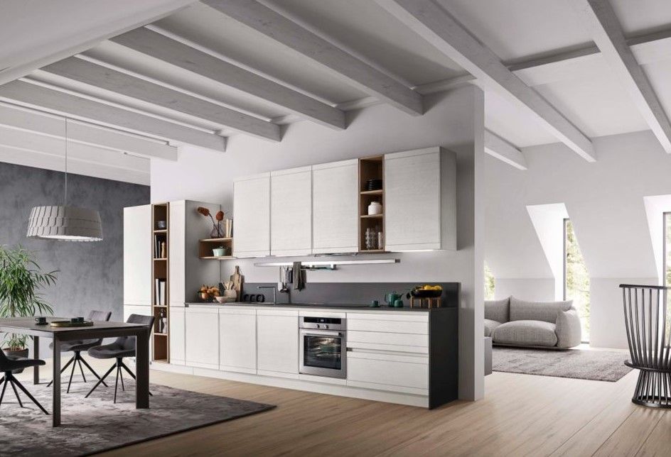 Una cucina con mobili bianchi, un tavolo, sedie e un divano.