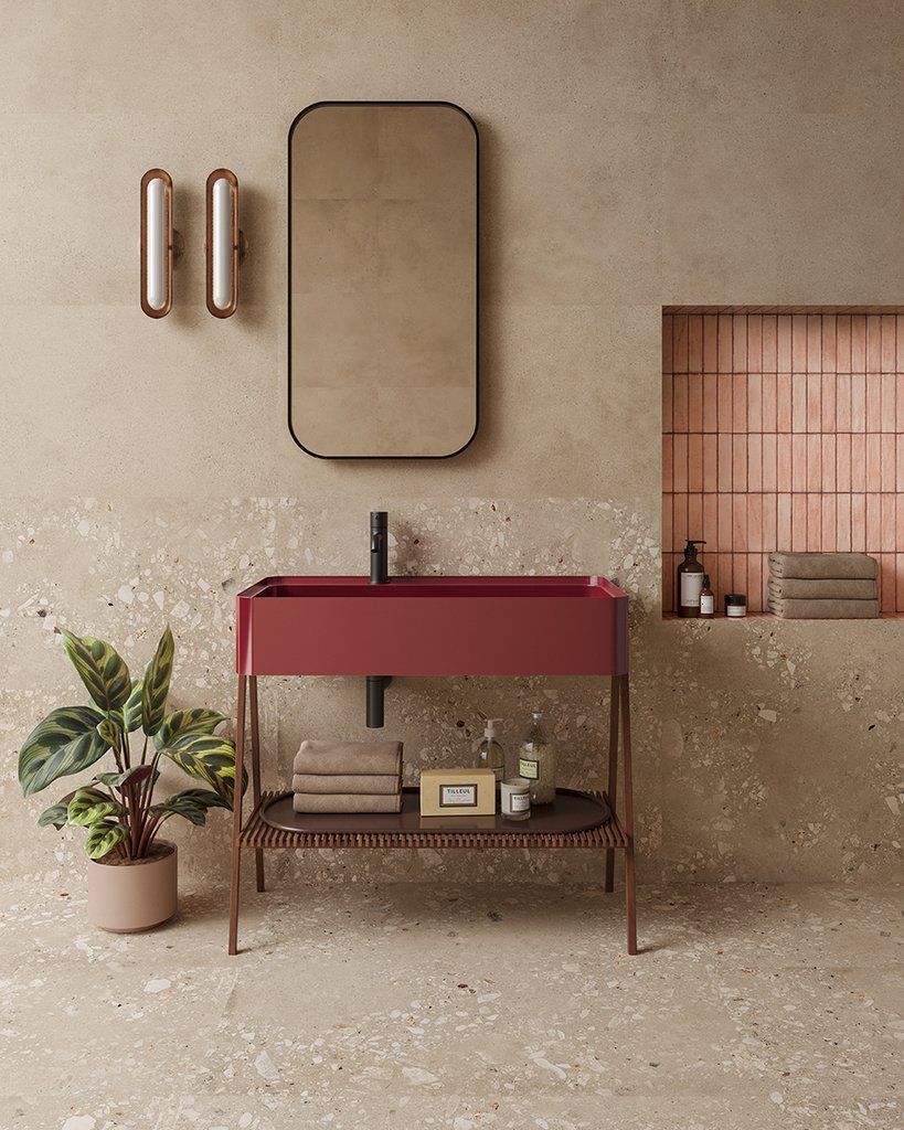 Un bagno con lavandino rosso, specchio e pianta.