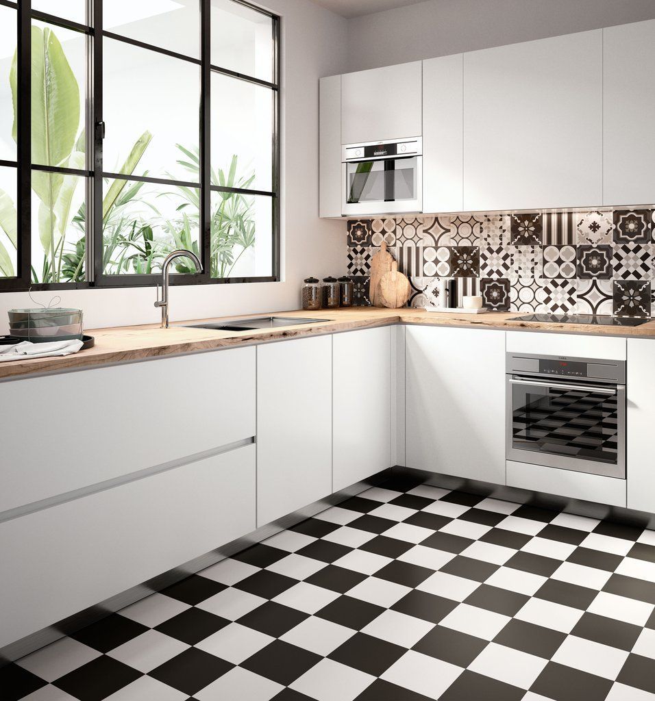 Una cucina con mobili bianchi e un pavimento a scacchi bianchi e neri.