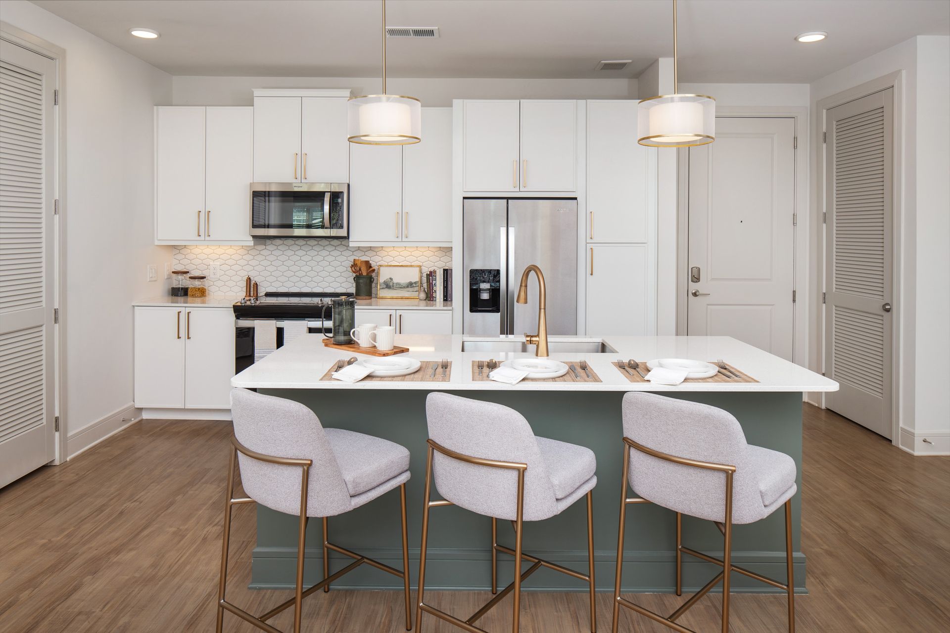 Modern white kitchen with island, barstools, stainless appliances, and light wood floors