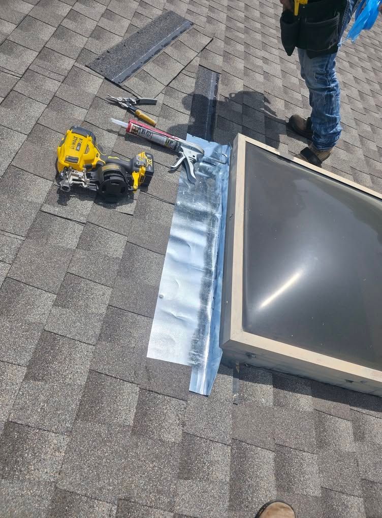 Roof with tools beside a skylight and a person standing nearby