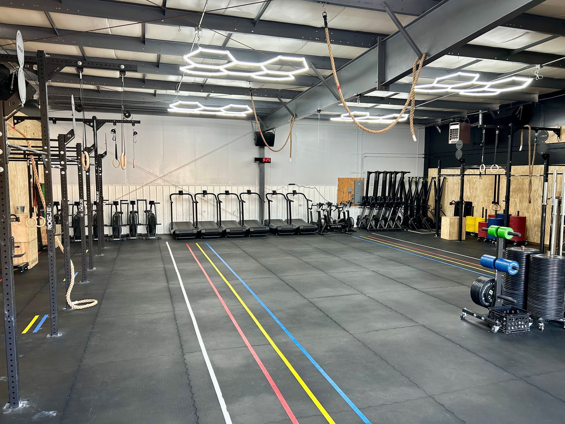 Inside Gray Duck CrossFit gym in Mankato, MN, with rowers, rigs, and black flooring marked by colorful lane lines.