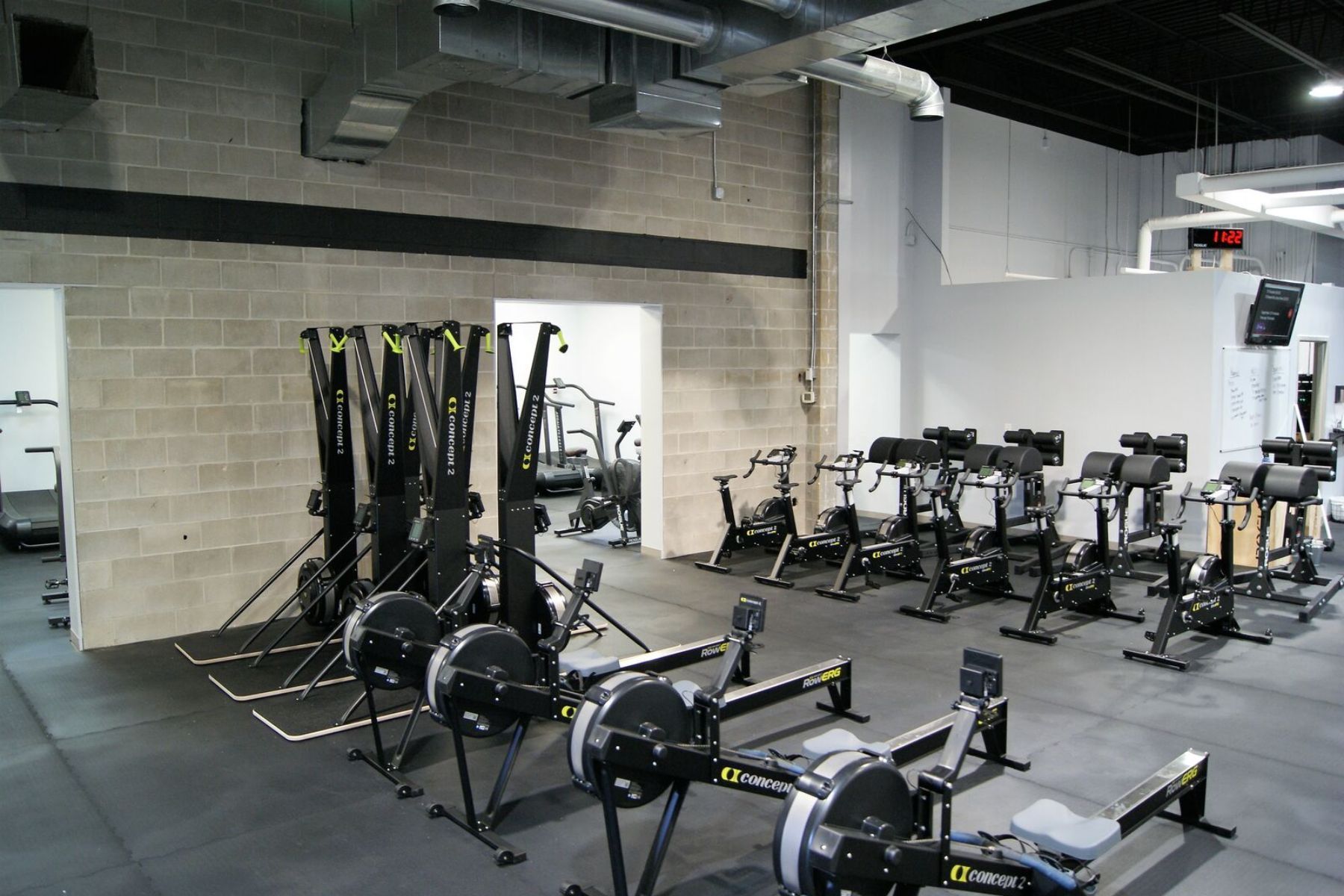 Empty Gray Duck CrossFit gym in Mankato, MN, with rowing machines and ski erg trainers on a black rubber floor