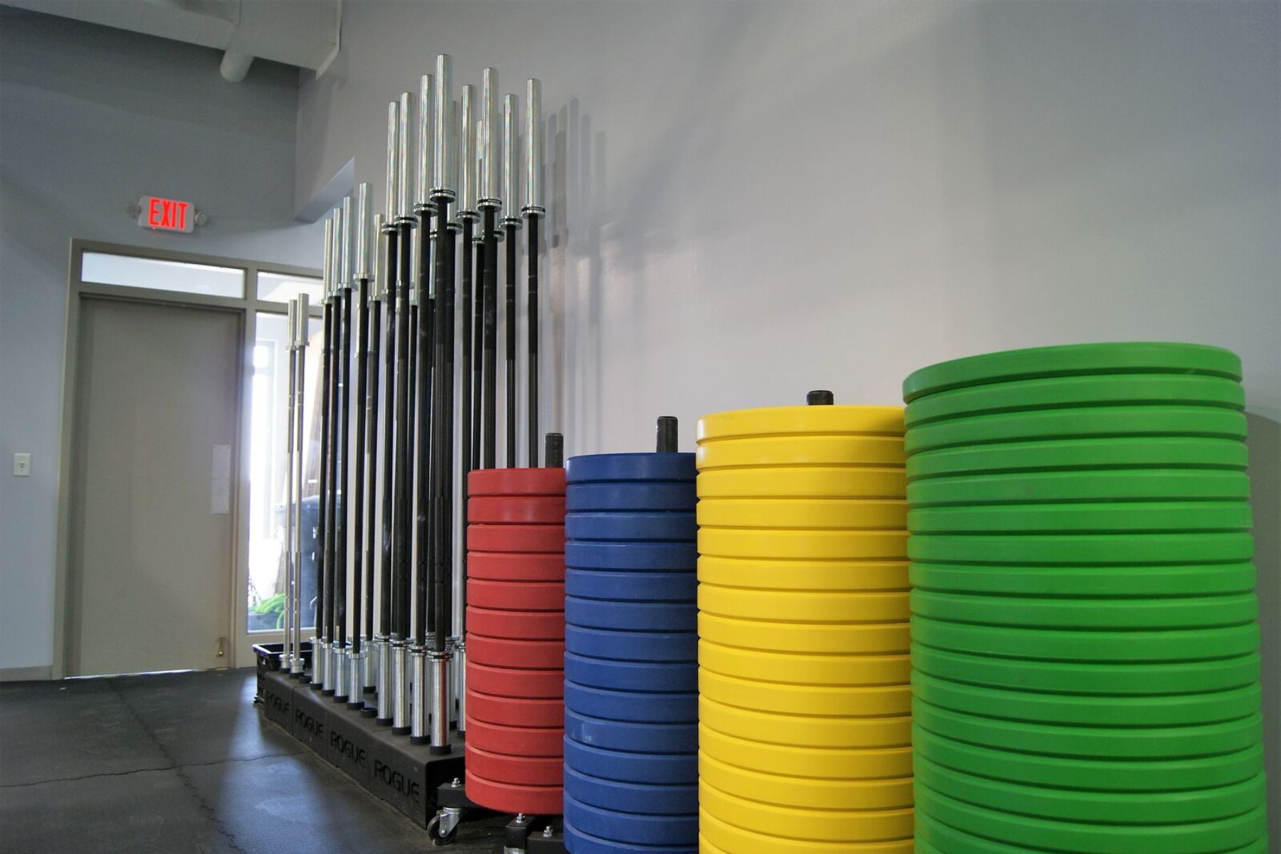 Stacked colorful gym weight plates beside storage racks in Gray Duck CrossFit gym in Mankato, MN, hallway
