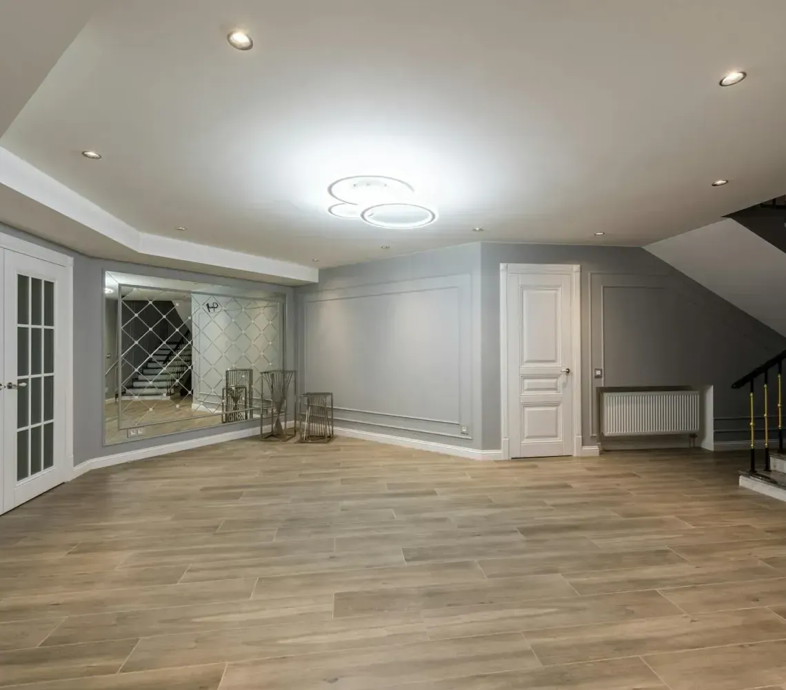 Empty modern living room with wood floors, gray walls, recessed lighting, and French doors