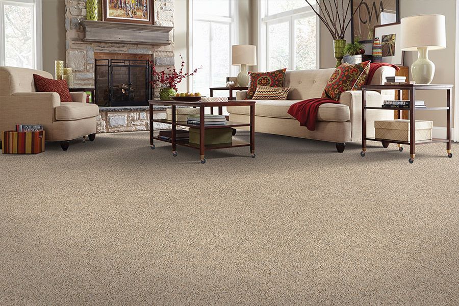 Cozy living room with beige sofas, fireplace, coffee table, lamp, and large carpeted floor