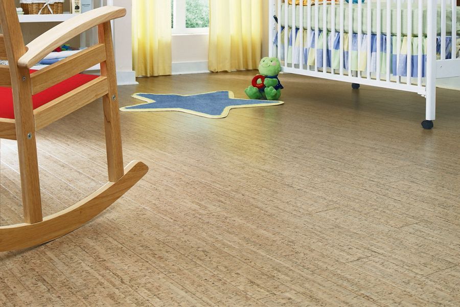 Cozy nursery with a wooden rocking chair, crib, toy, and sunlight on the floor
