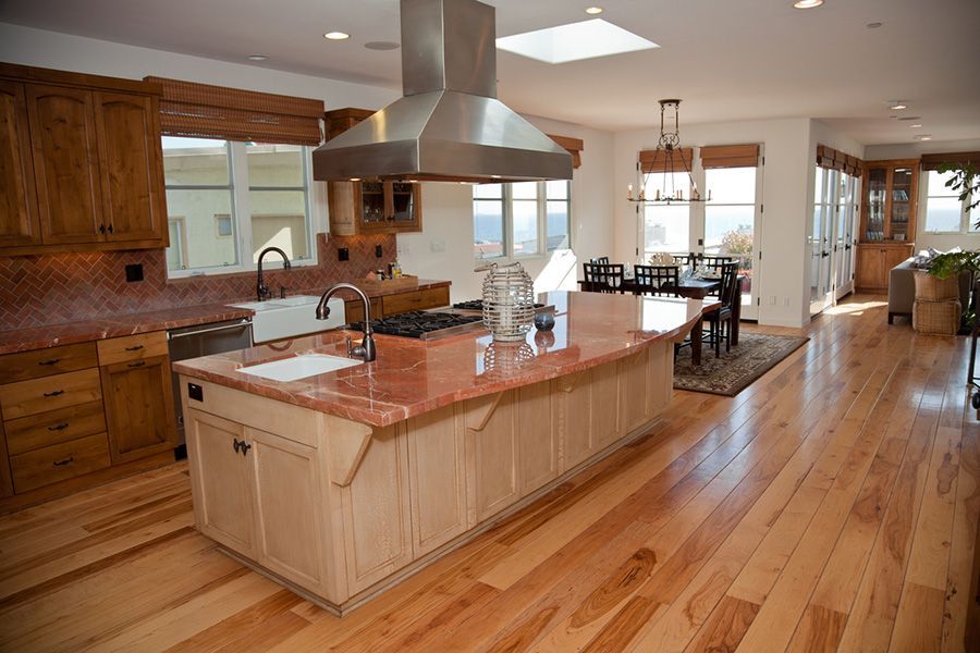 Spacious modern kitchen with wood cabinets, granite island, stainless hood, and hardwood floors