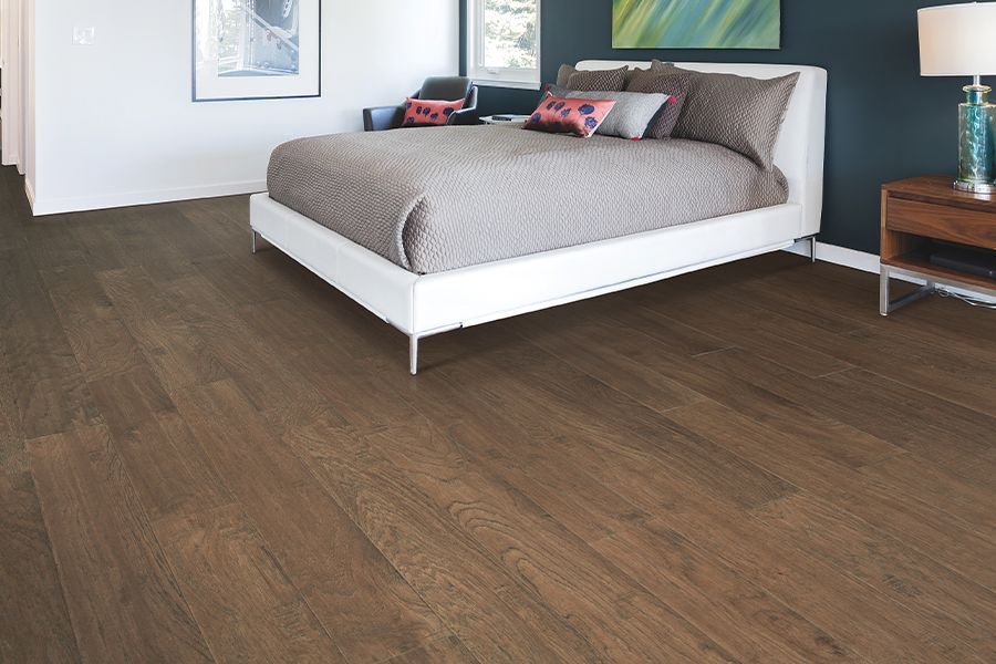 Modern bedroom with a bed, dark wood floor, and framed wall art