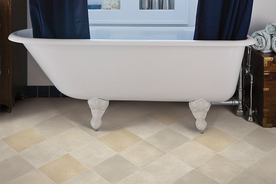 White clawfoot bathtub in a bathroom with blue curtains and patterned tile floor
