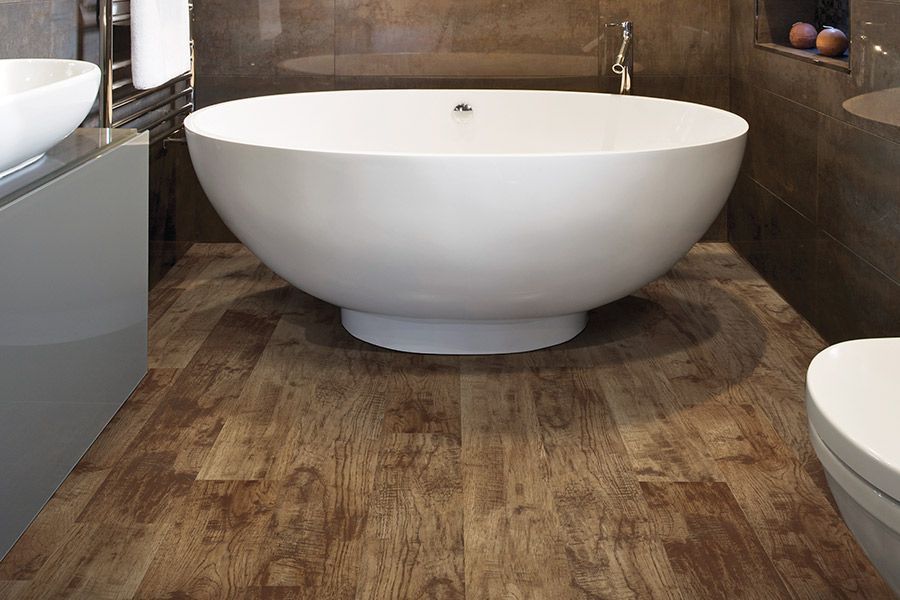 Modern bathroom with a white freestanding oval tub and wood-look flooring