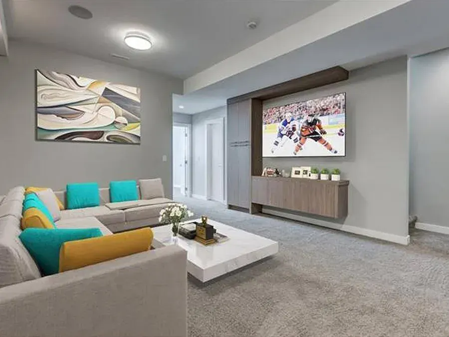 Modern living room with gray sofa, teal and mustard cushions, wall-mounted TV, and abstract art.
