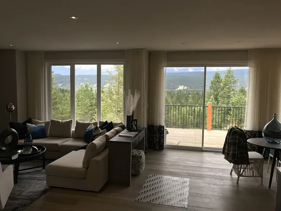 Spacious modern living room with large windows, sectional sofa, and mountain view through sliding doors