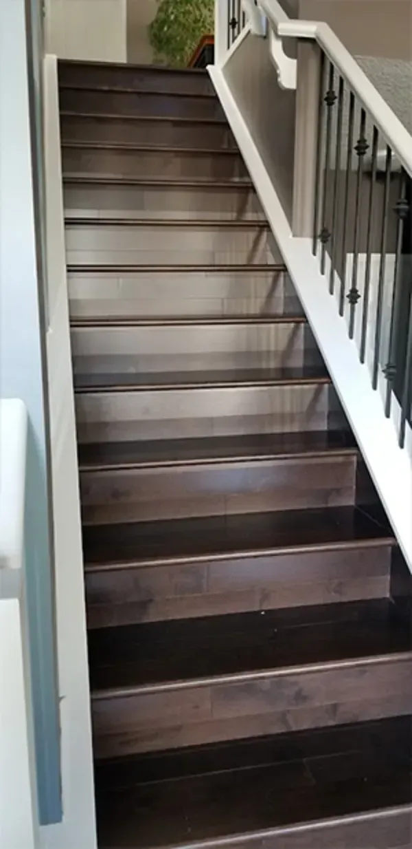 Wooden staircase with dark steps and white railing leading upward indoors