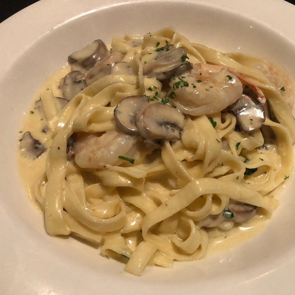 A Plate of Pasta With Mushroom Sauce and Parsley on a Table — Romanas Italian Restaurant in Mermaid Beach, QLD