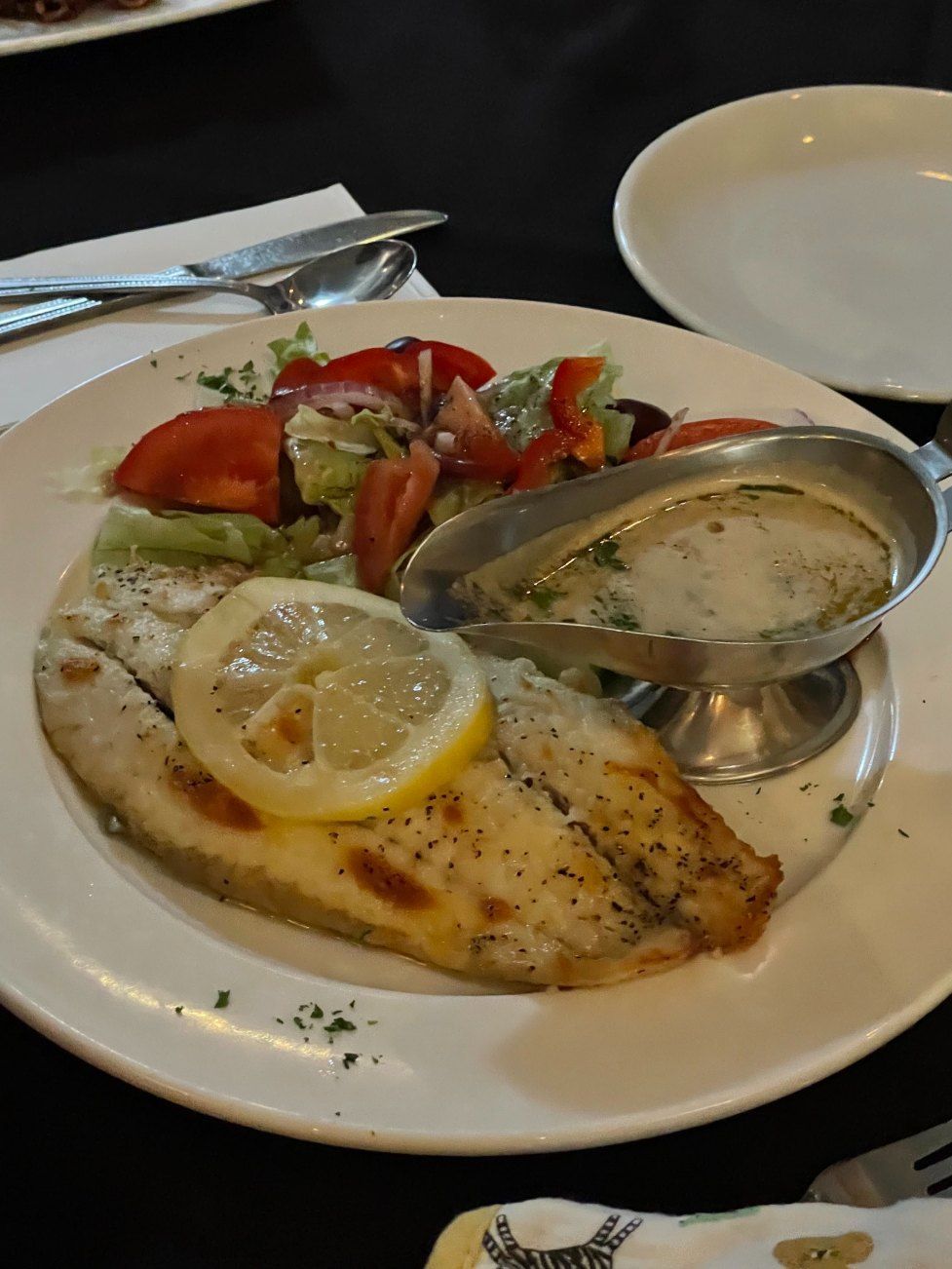 A White Plate Topped With a Piece of Fish and a Lemon Slice — Romanas Italian Restaurant in Mermaid Beach, QLD