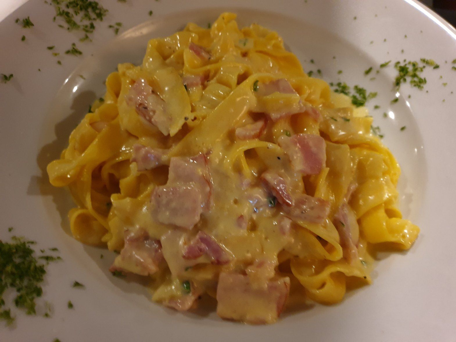Creamy pasta with ham and parsley in a white bowl — Romanas Italian Restaurant in Mermaid Beach, QLD