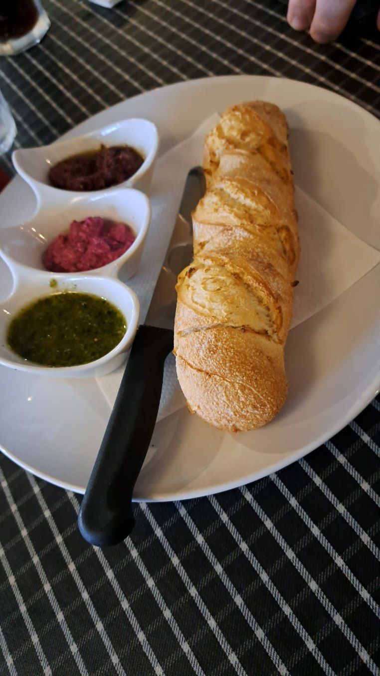 Breadsticks with three dipping sauces on a white plate, with a black knife on a checkered tablecloth. — Romanas Italian Restaurant in Mermaid Beach, QLD
