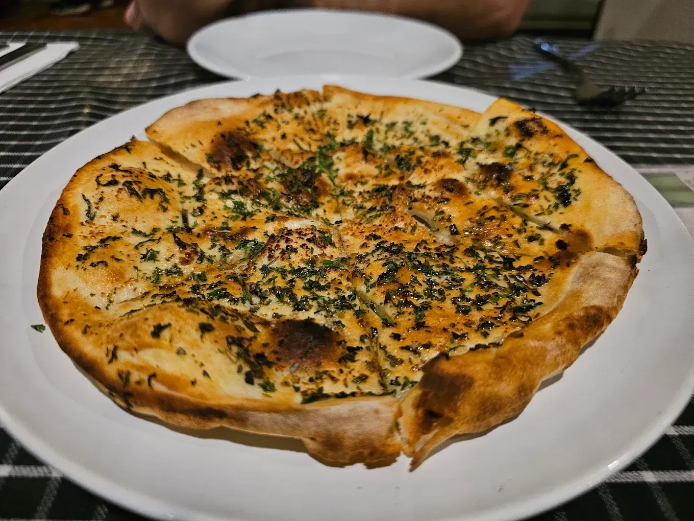 Cheese and Herb Pizza on a White Plate at a Table — Romanas Italian Restaurant in Mermaid Beach, QLD