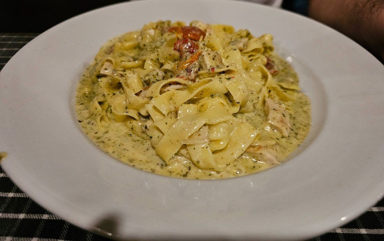 A White Plate Topped With Pasta and Sauce on a Table — Romanas Italian Restaurant in Mermaid Beach, QLD