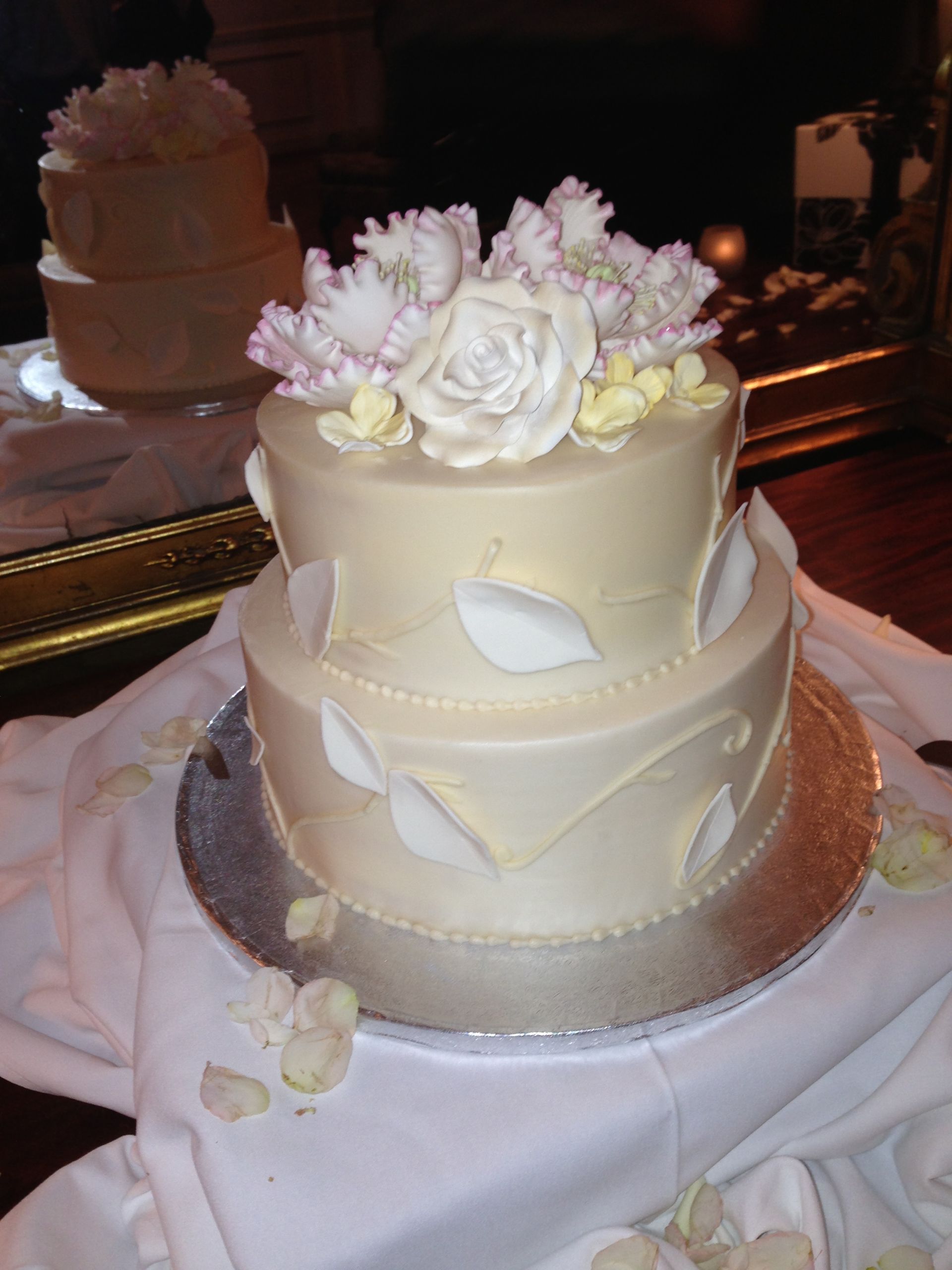 a white wedding cake with flowers and leaves on top
