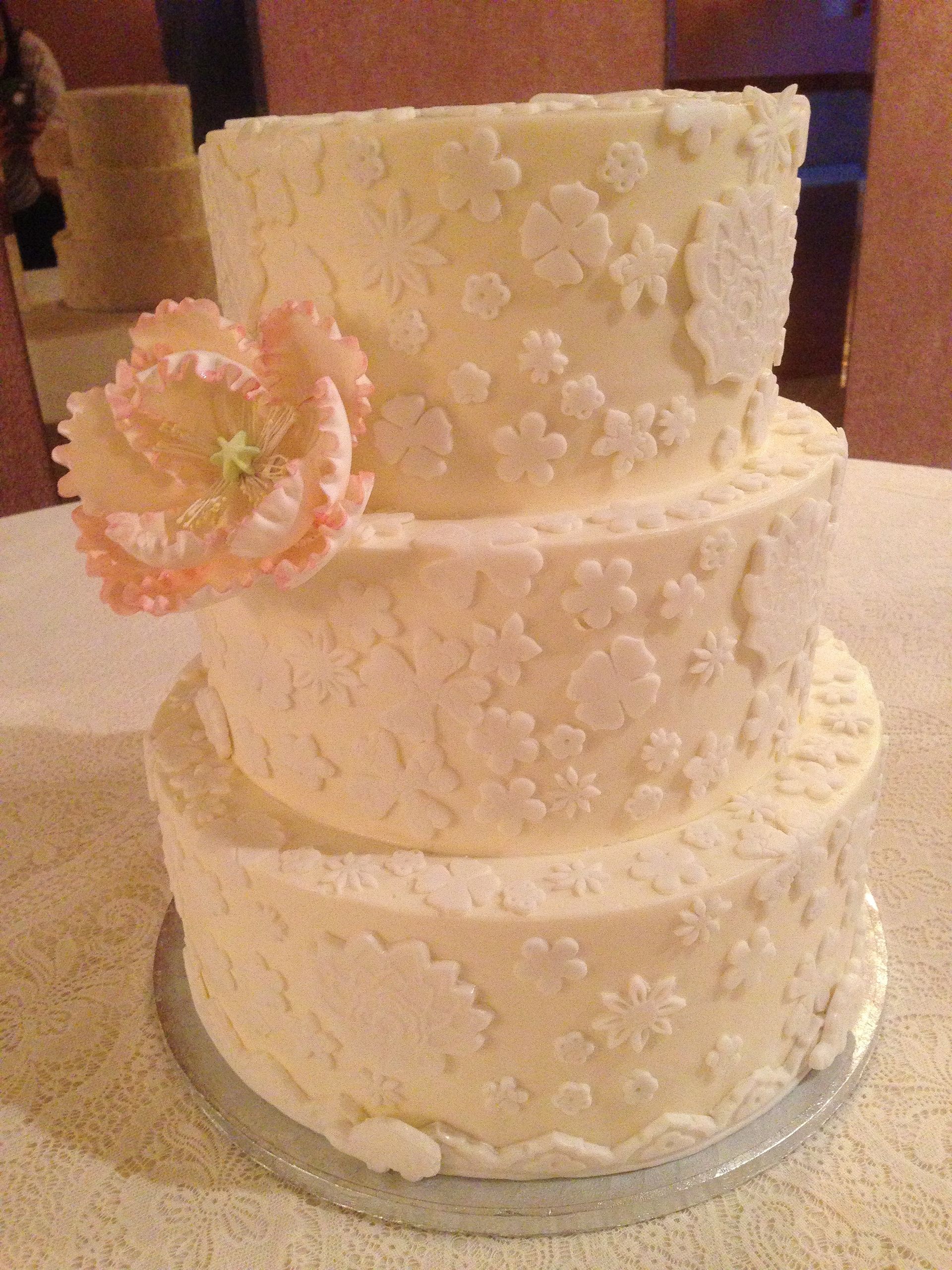 a white wedding cake with a pink flower on top