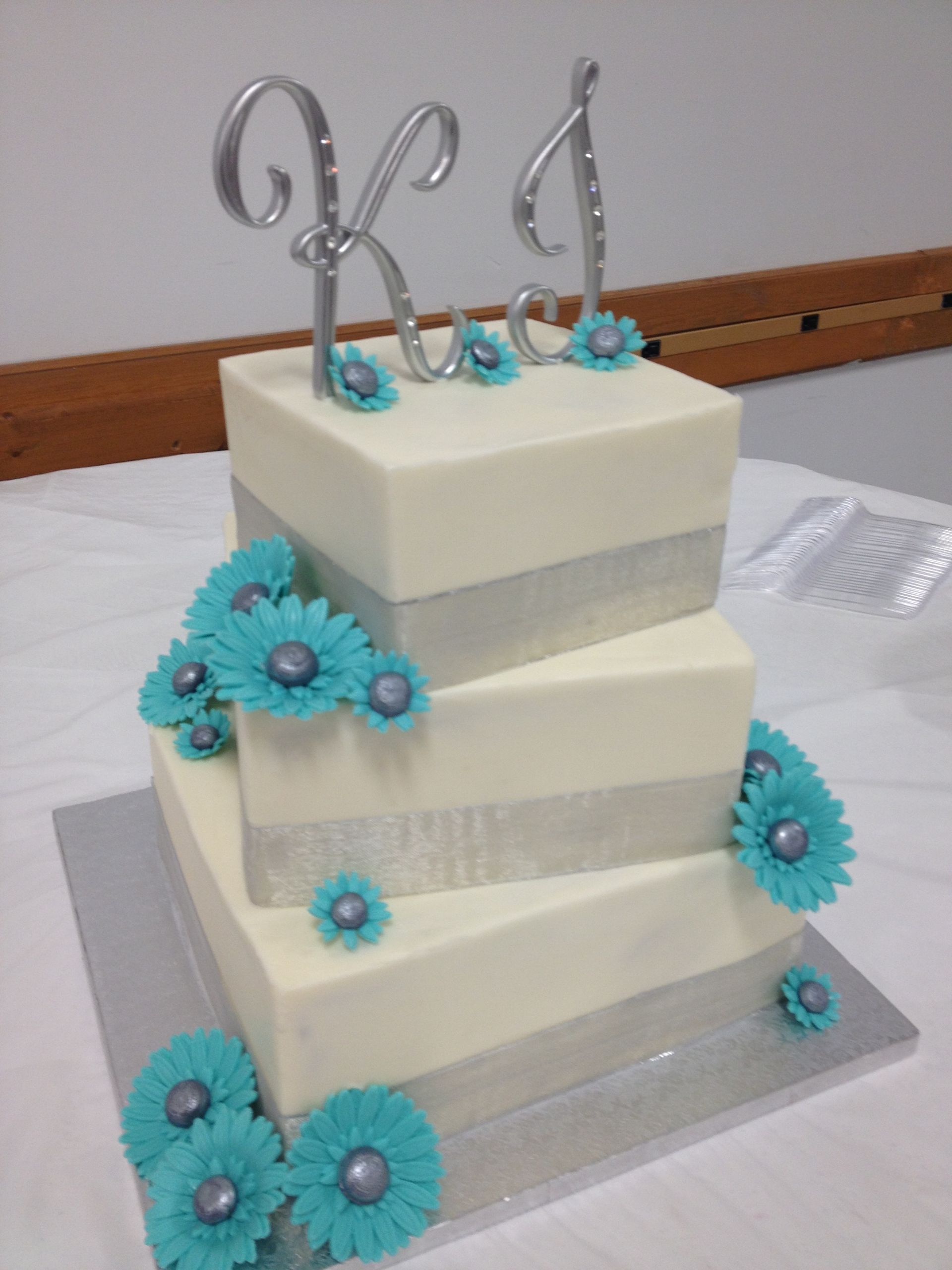 a wedding cake with blue flowers and silver ribbon