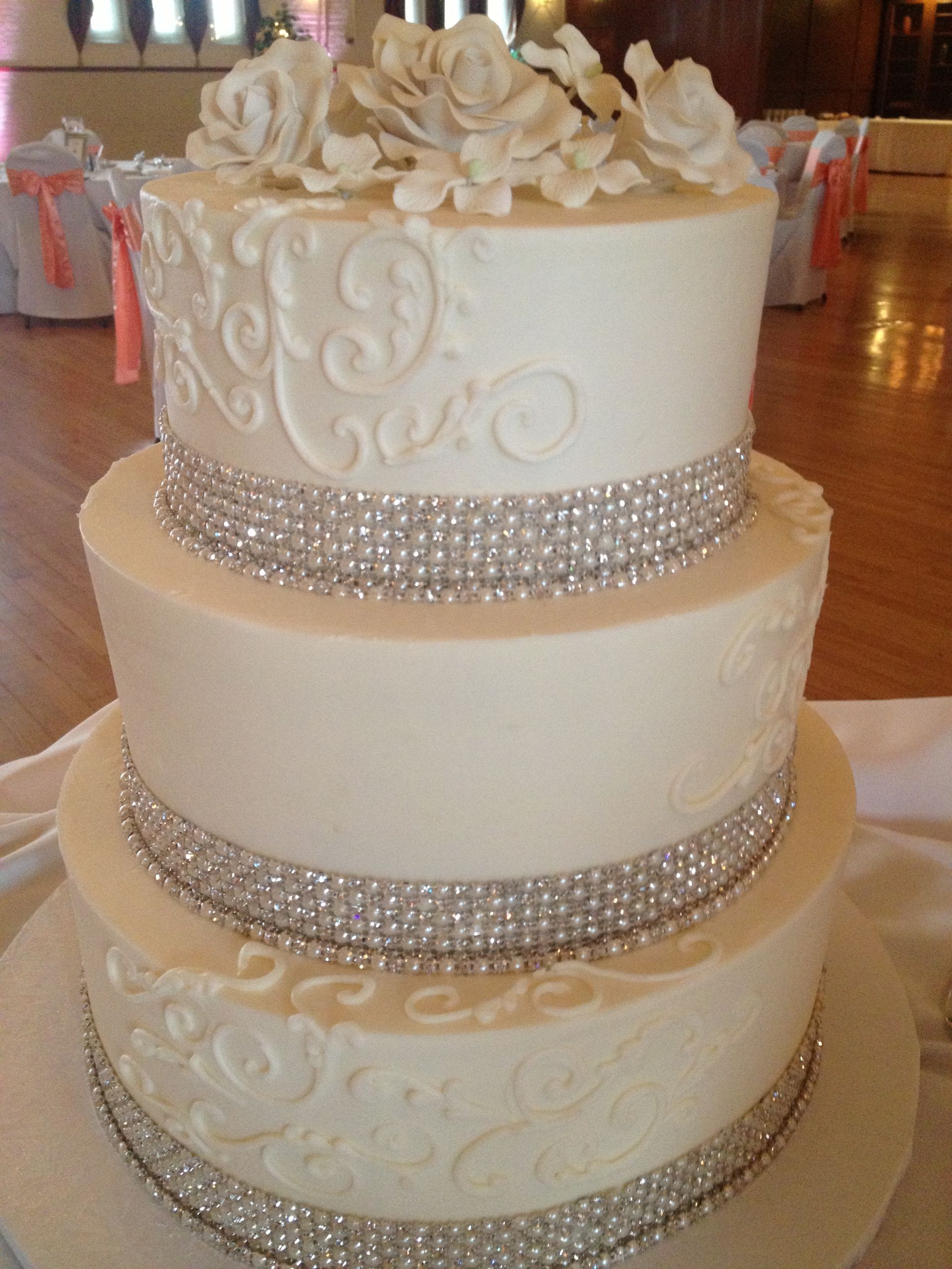 a white wedding cake with flowers and rhinestones on it