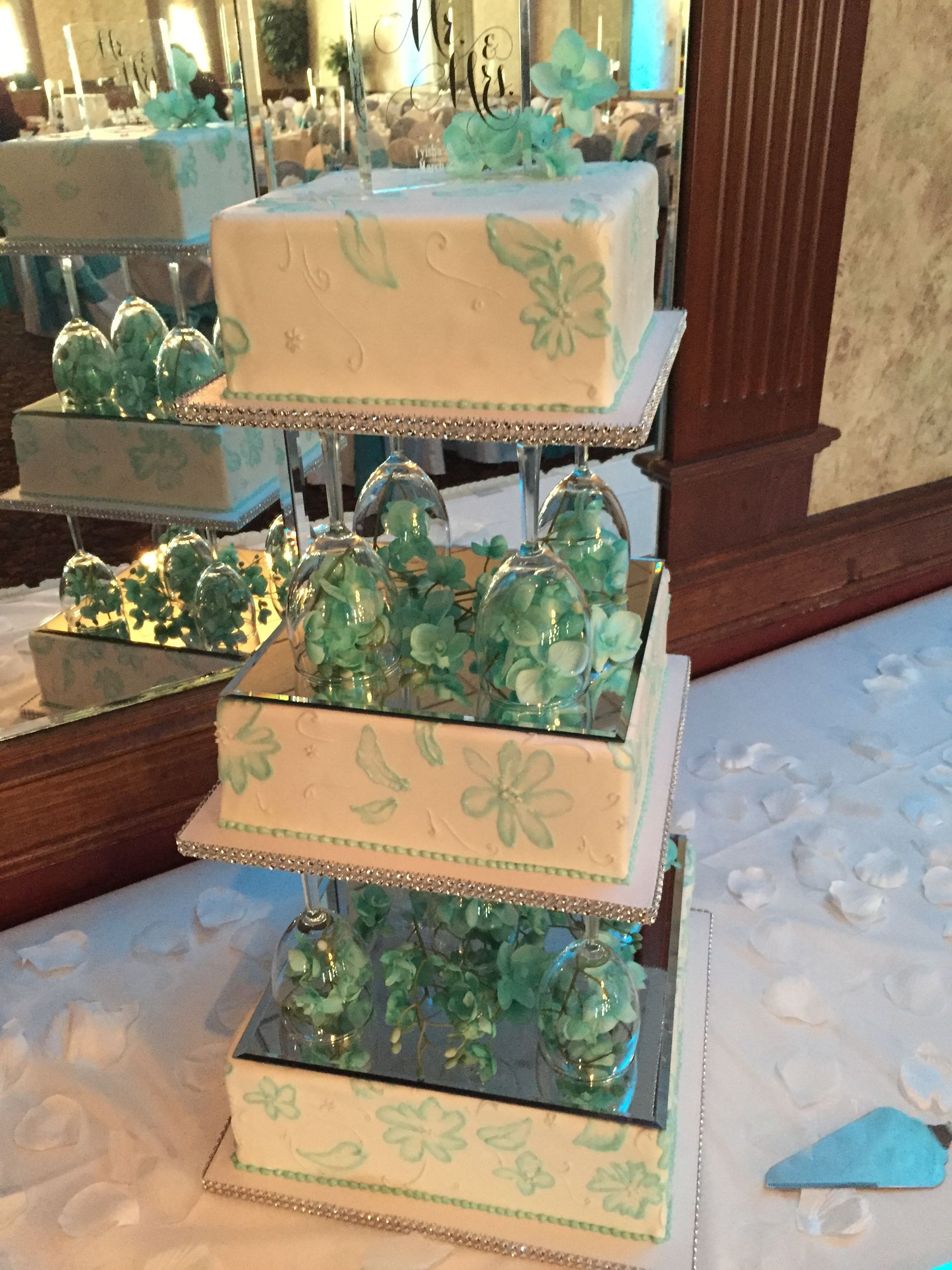 a four tiered wedding cake with green flowers on it