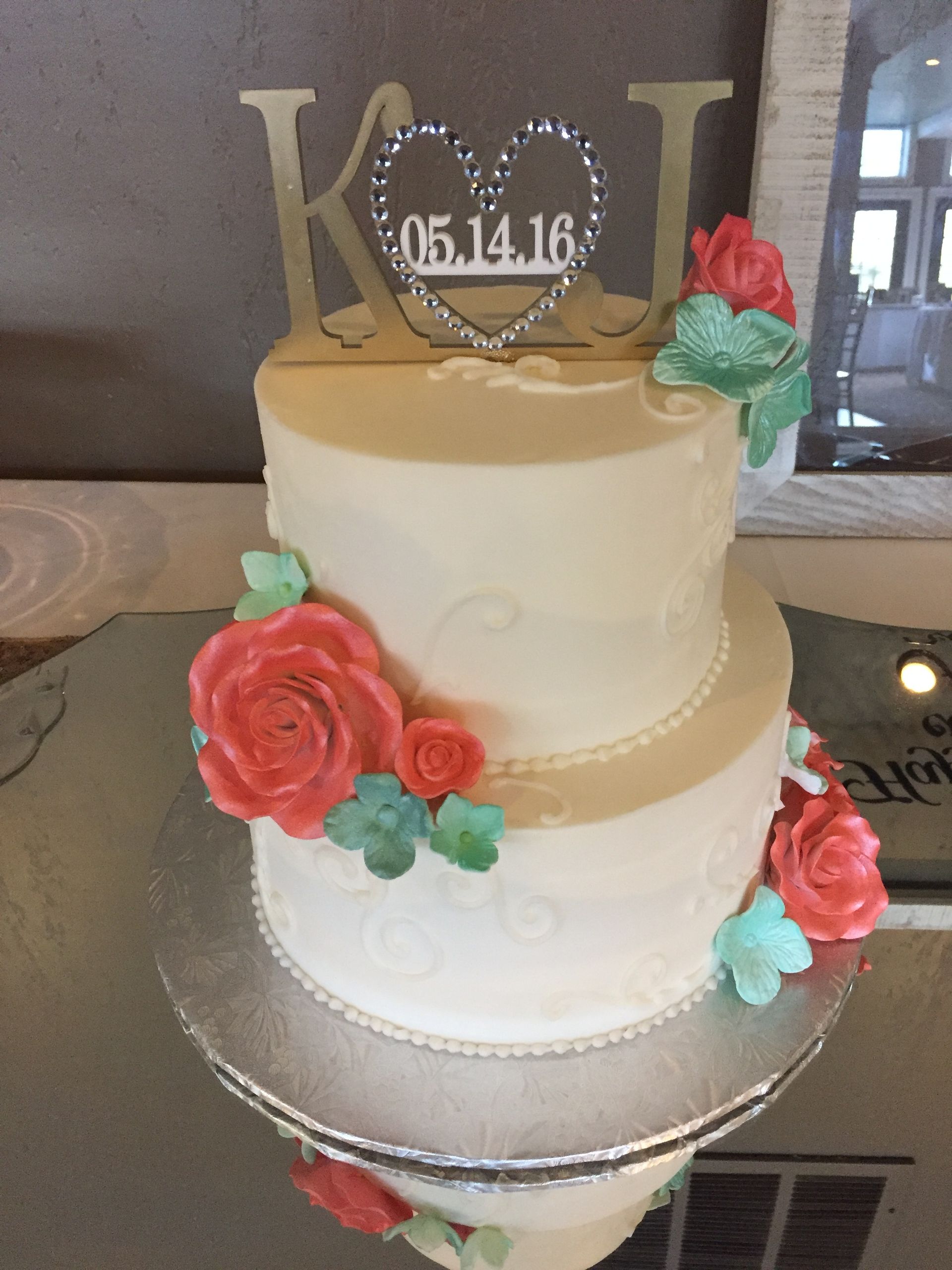 a wedding cake with flowers and a k and i topper