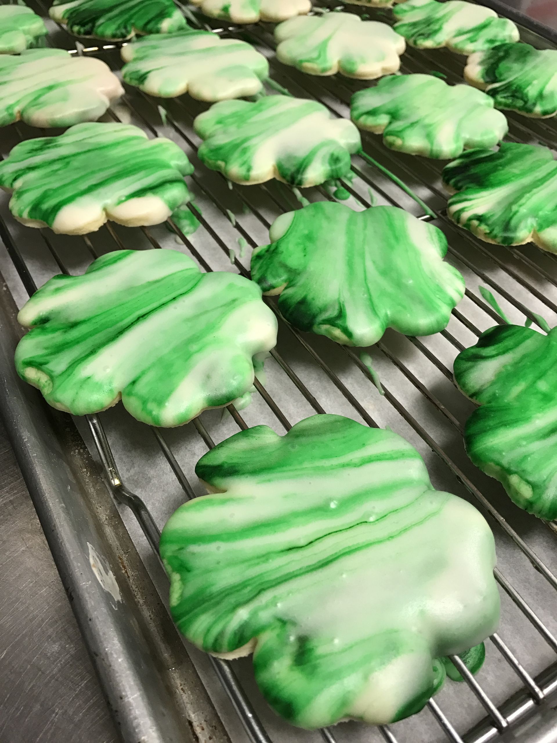 a bunch of green and white cookies on a cooling rack
