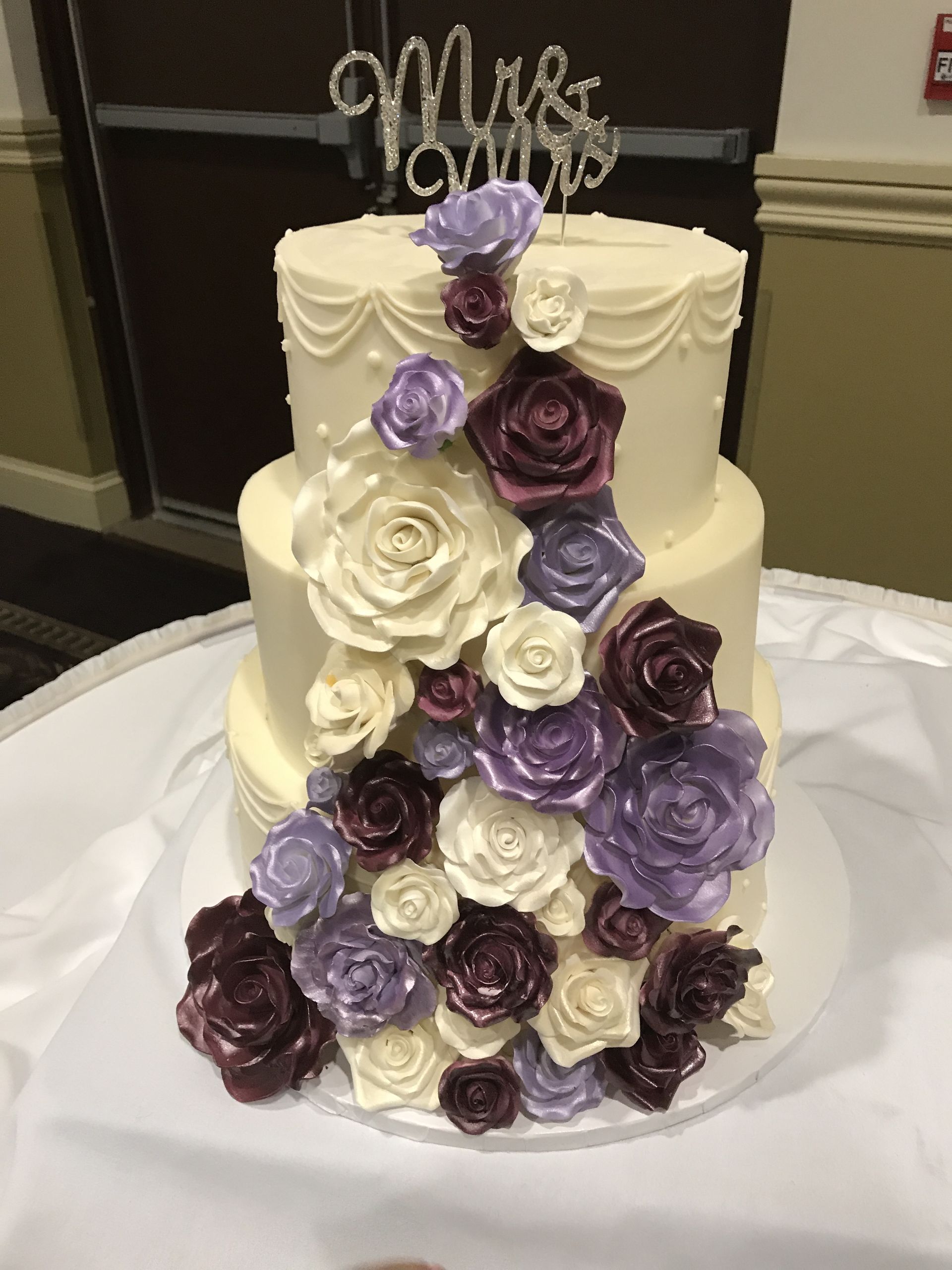 a wedding cake with purple and white roses on it