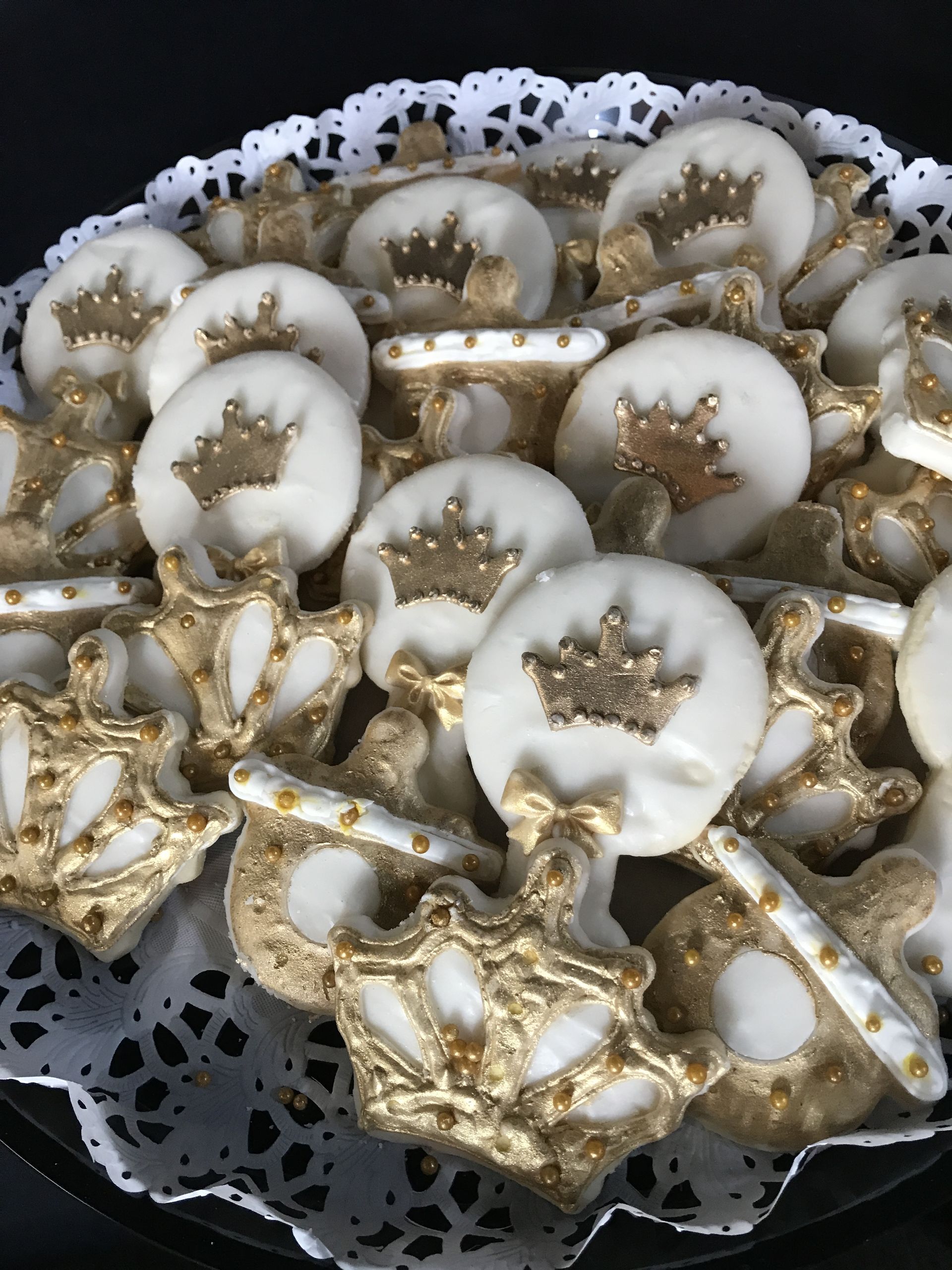 a plate of white cookies with gold crowns on them