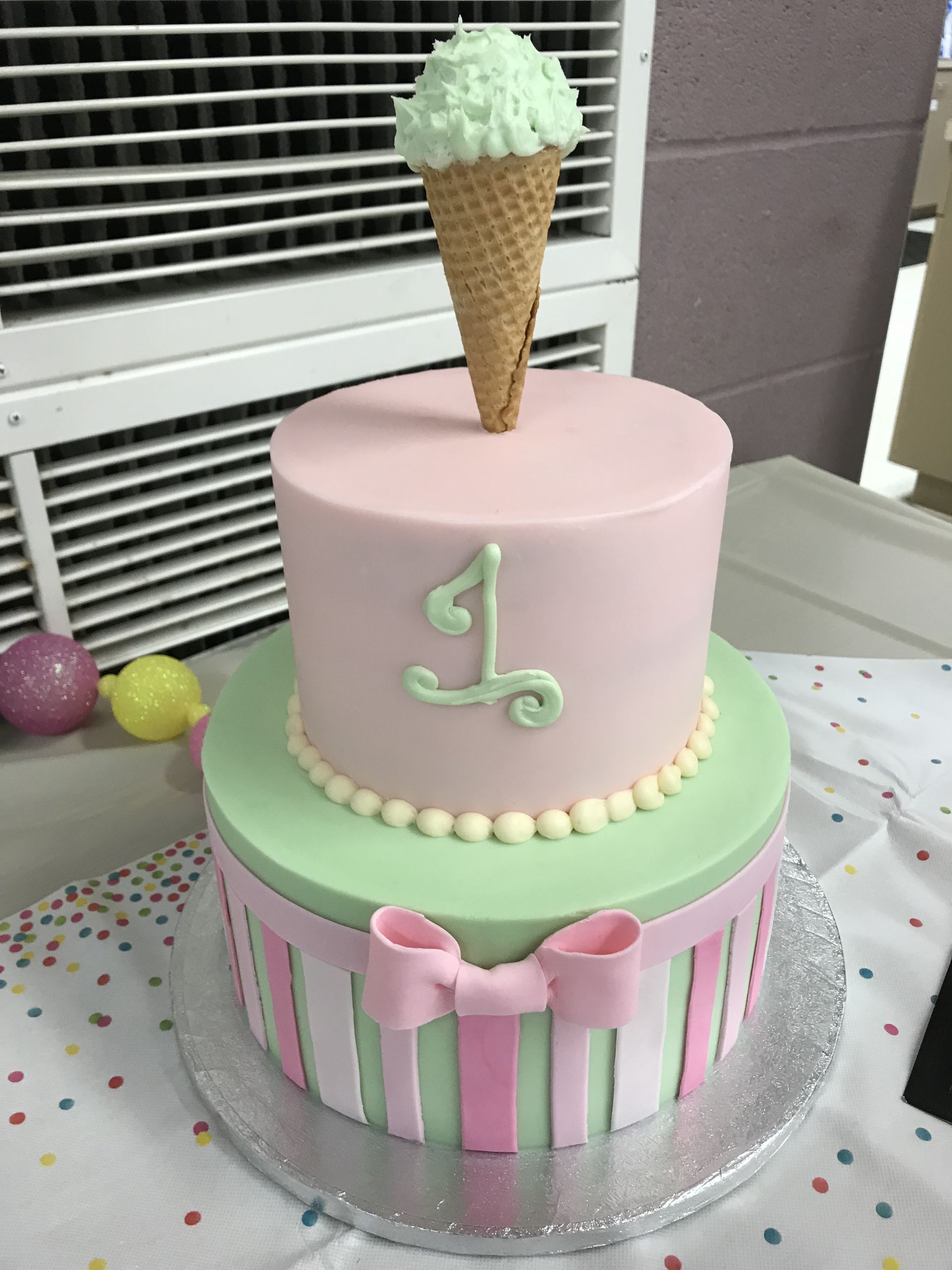 a pink and green cake with an ice cream cone on top