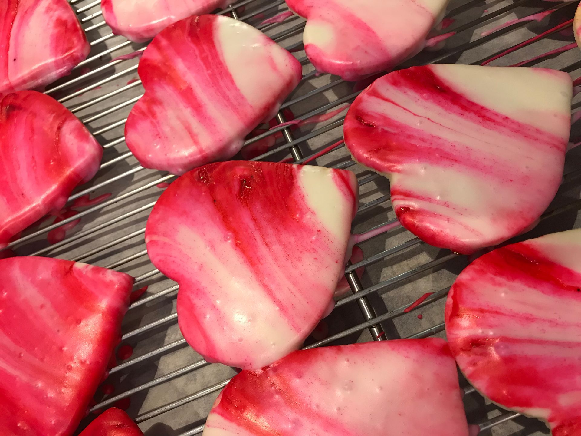 a bunch of heart shaped cookies are sitting on a cooling rack .