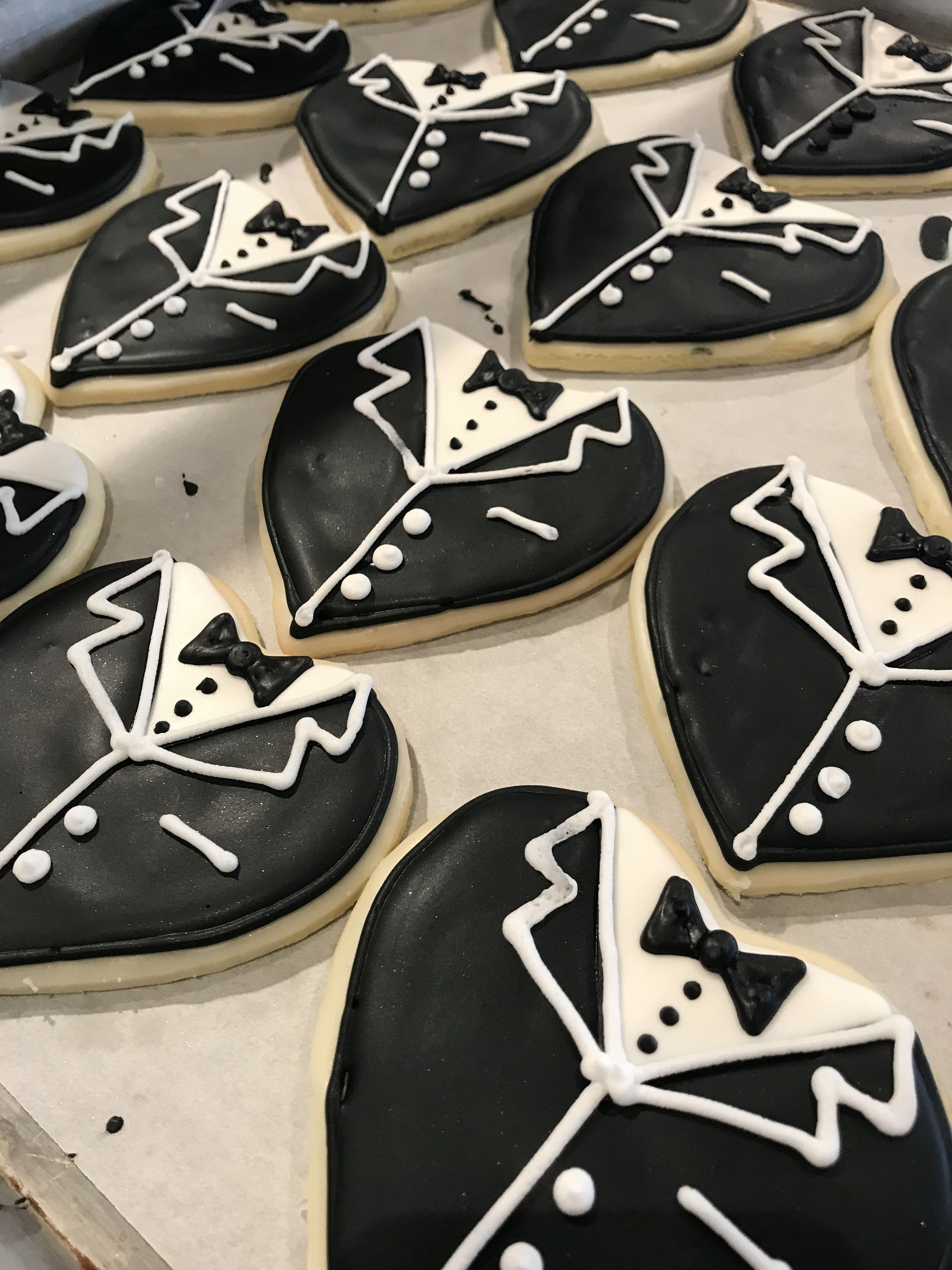 a bunch of black and white heart shaped cookies with tuxedos on them