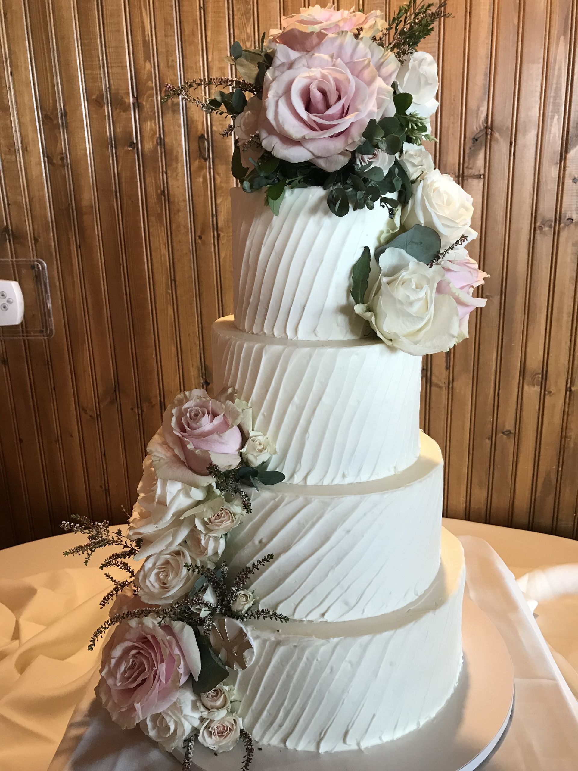 a white wedding cake with pink roses on top is sitting on a table .