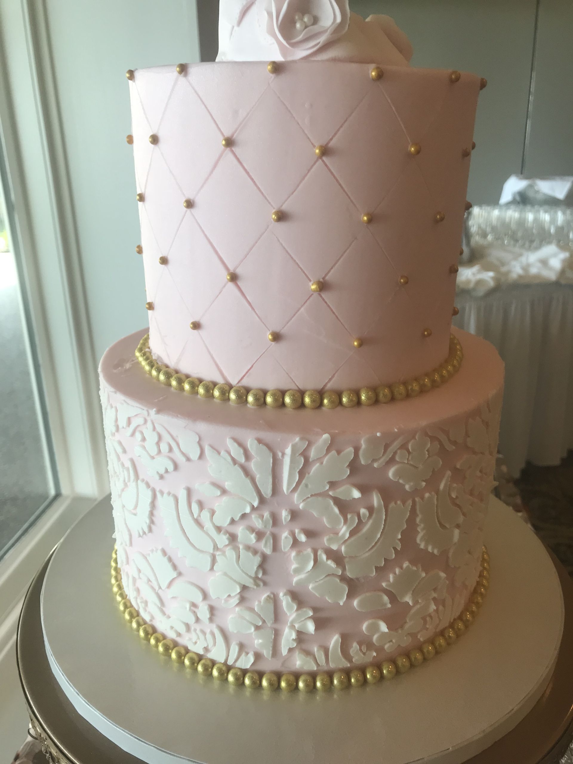 a pink and white cake with gold beads on it