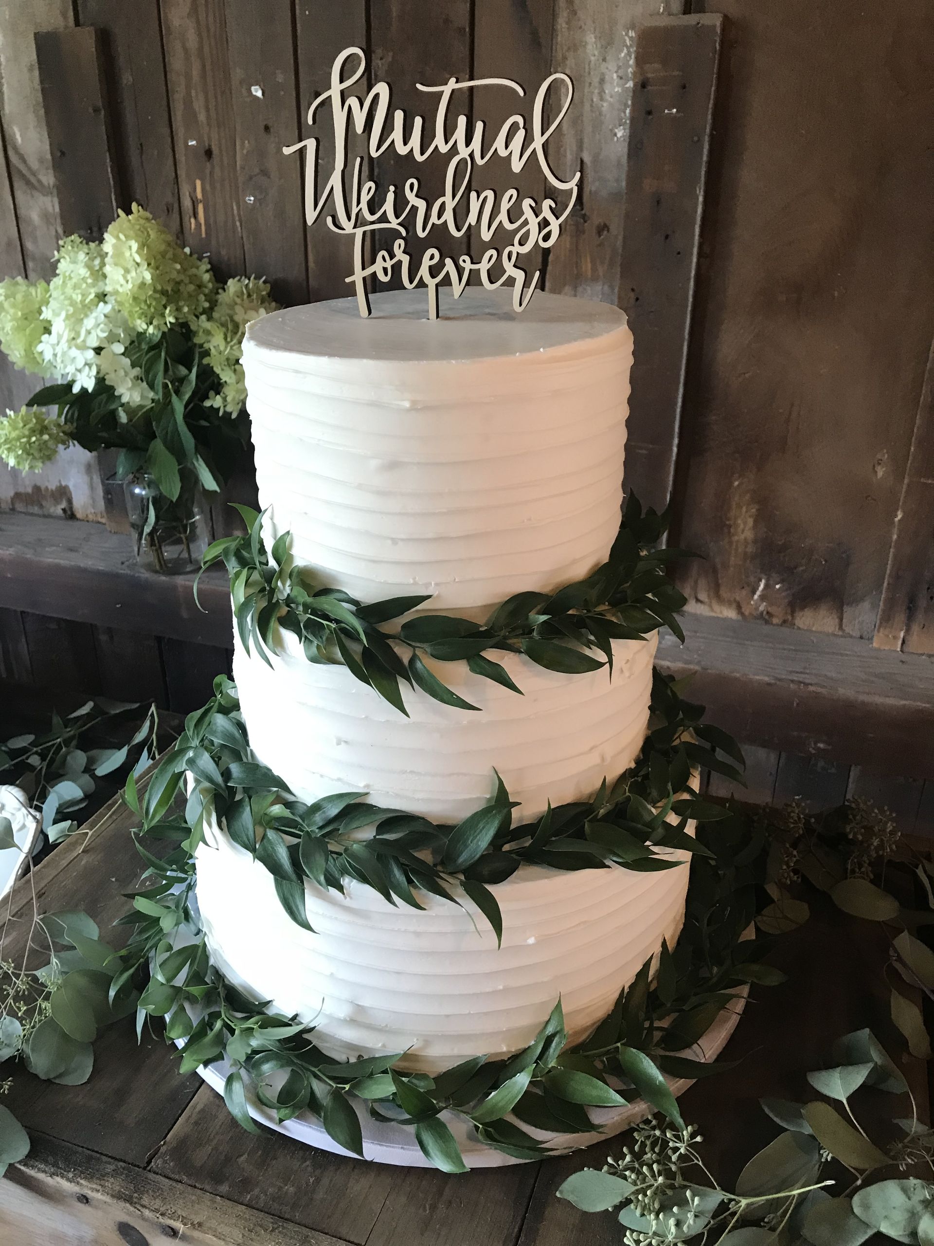 a three tiered wedding cake with a cake topper is sitting on a wooden table .