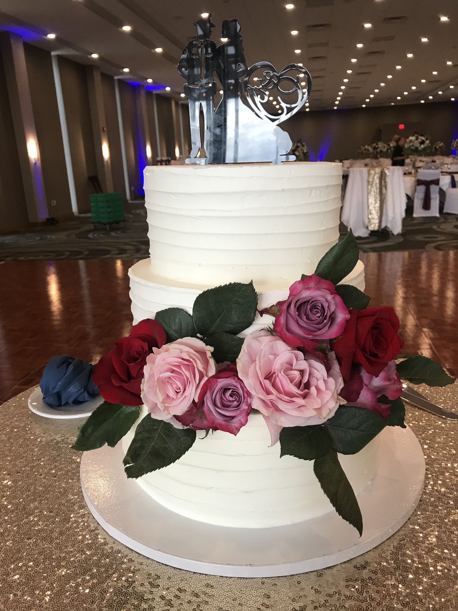 a white wedding cake with pink and red roses on it