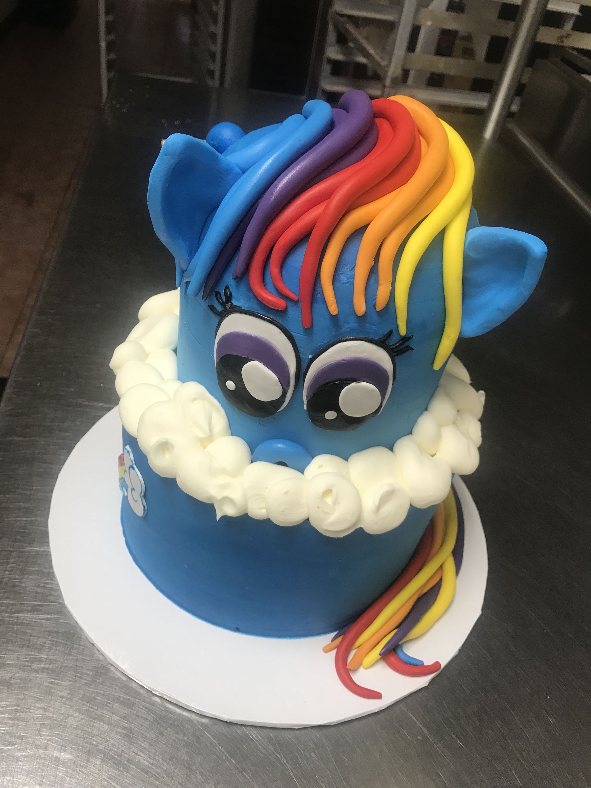 a blue cake with a rainbow mane and tail