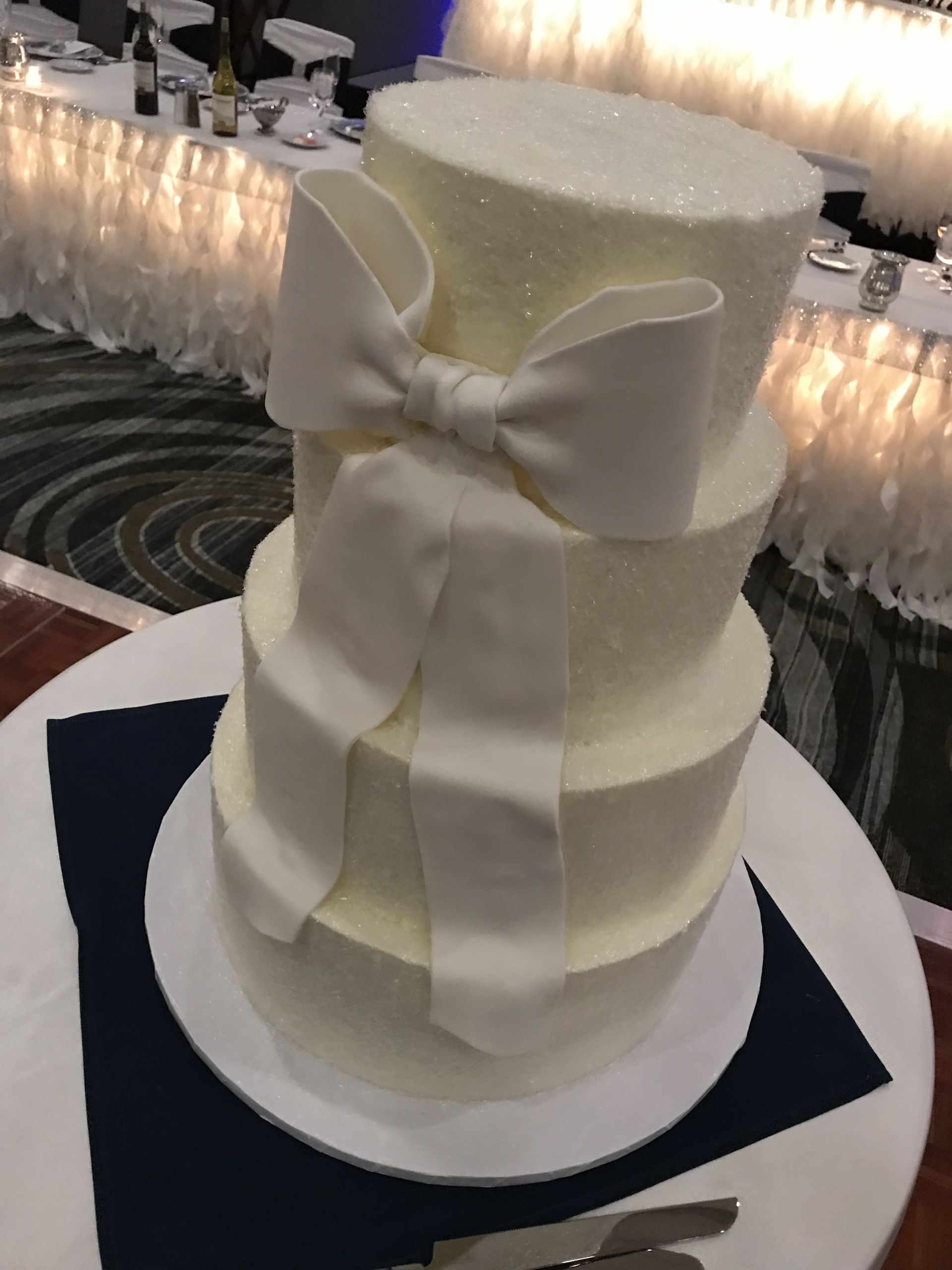 a white wedding cake with a bow on it is sitting on a table .