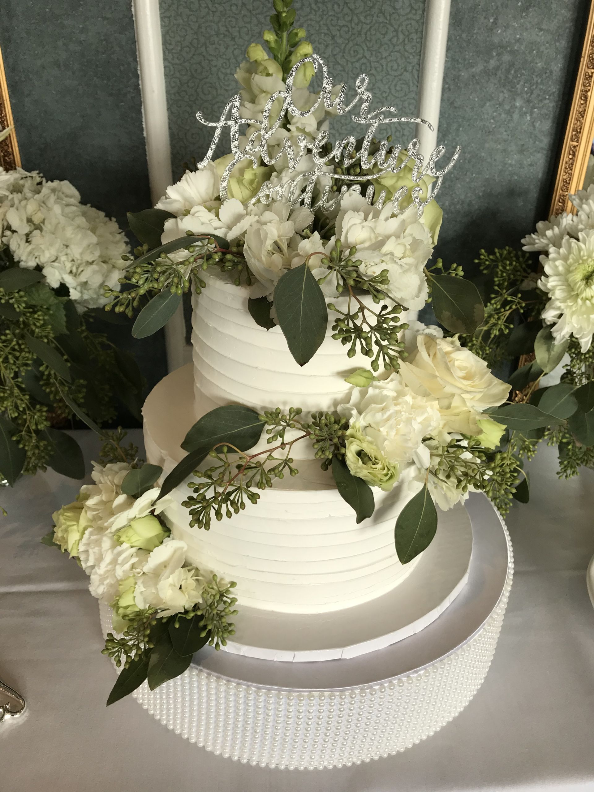 a wedding cake decorated with white flowers and greenery