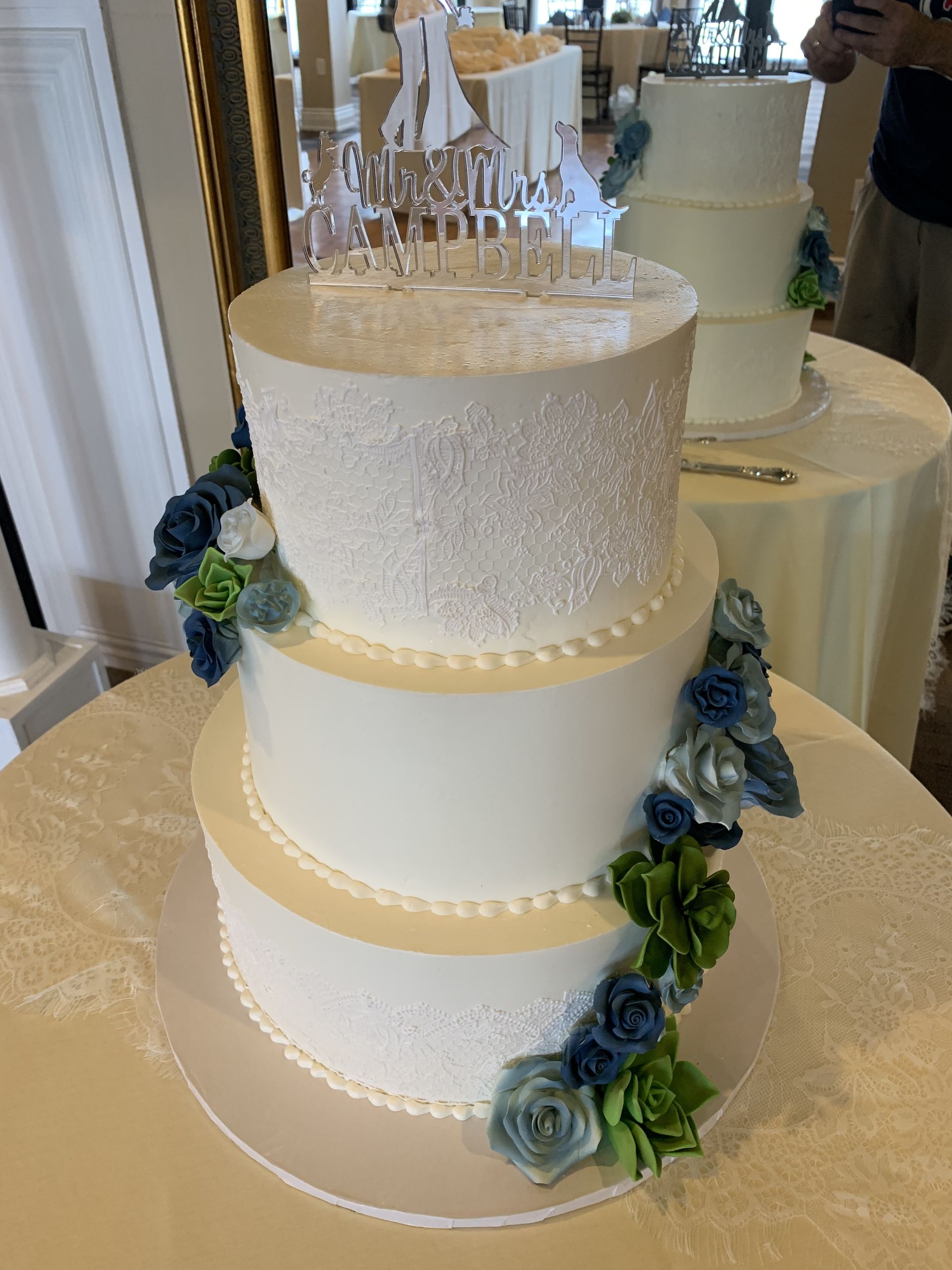a white wedding cake with blue flowers is on a table .