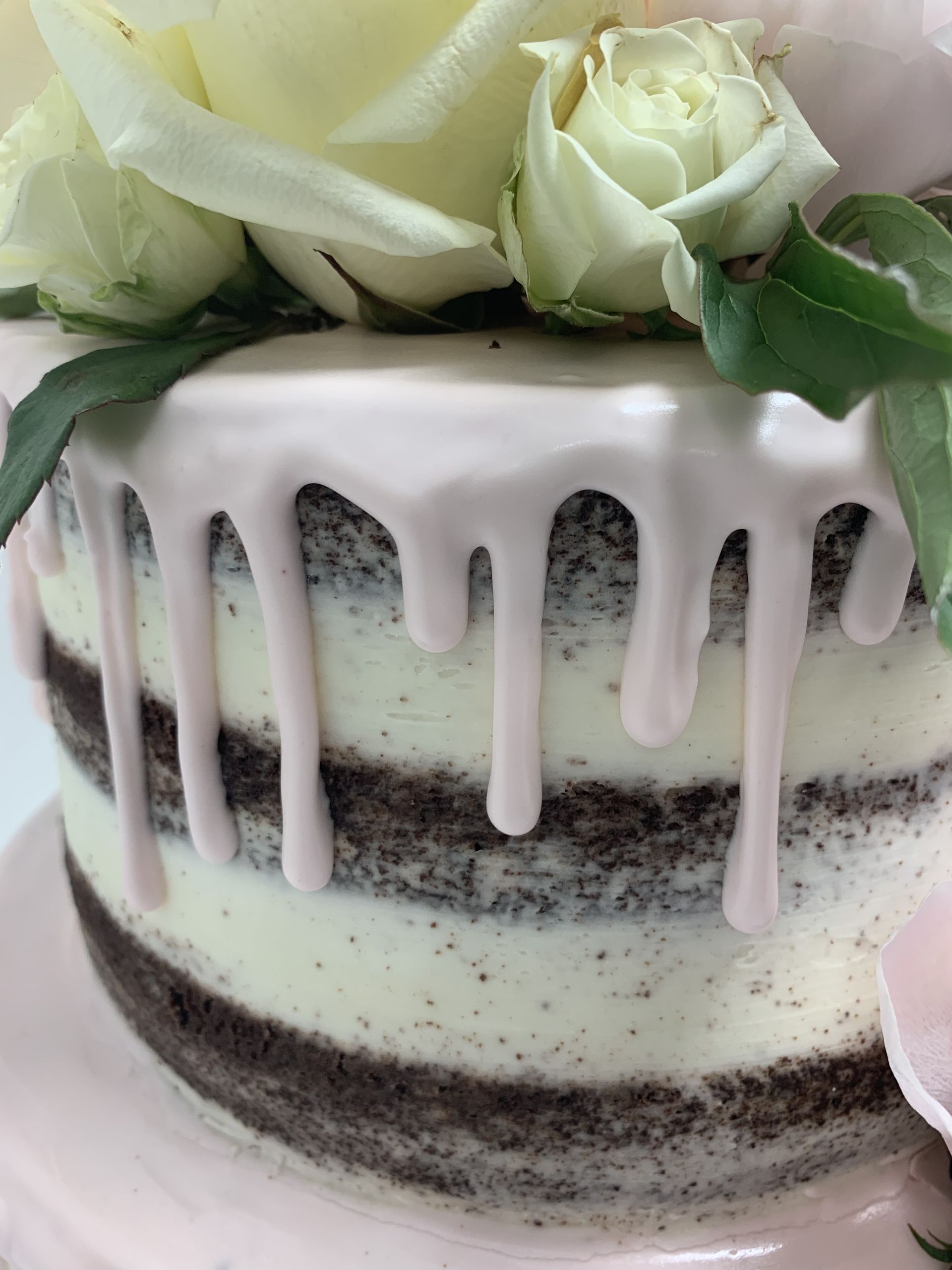 a close up of a cake with white frosting and flowers on top .