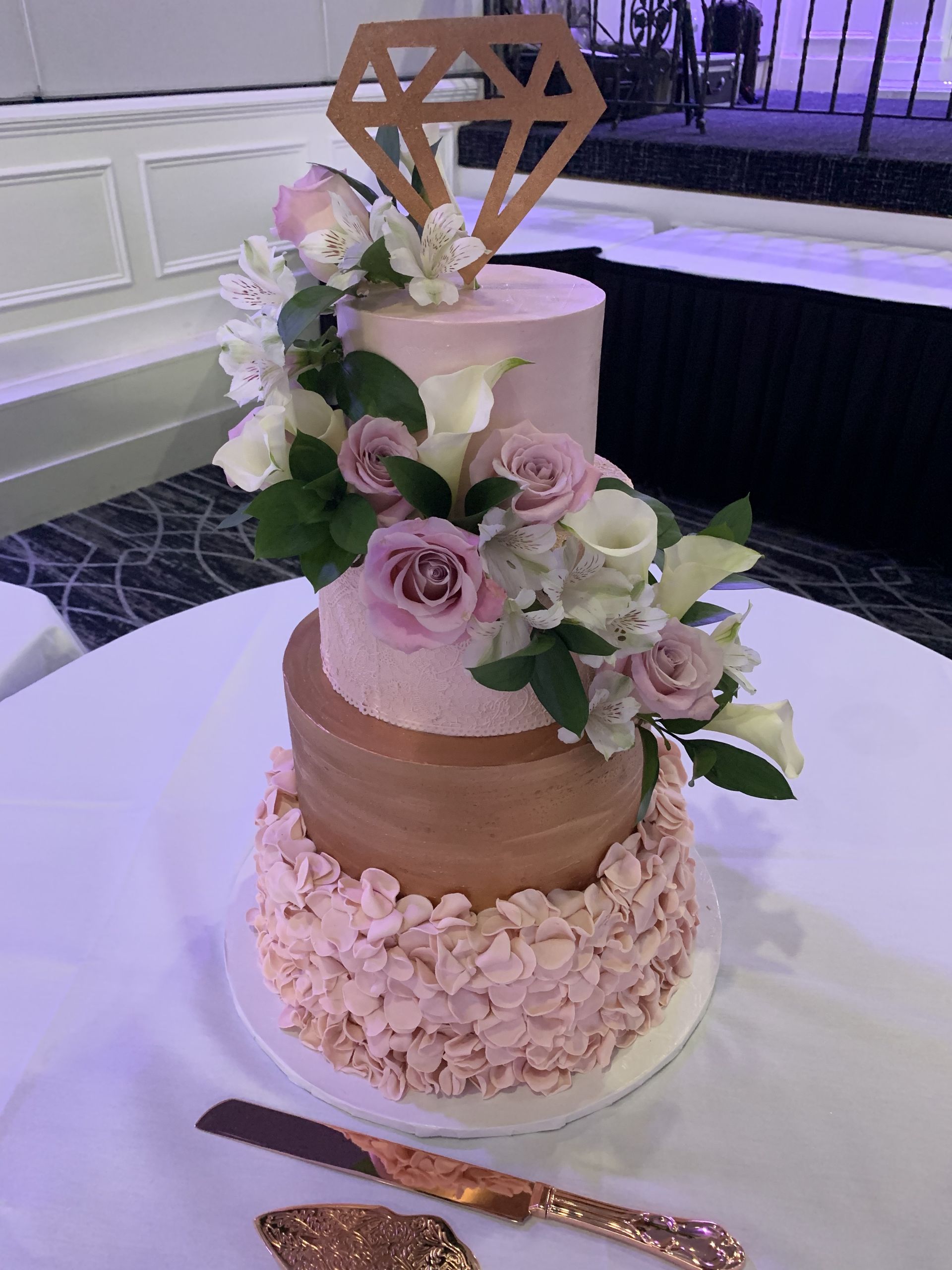a wedding cake with flowers and a diamond topper is on a table .